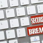 White computer keyboard with red keys that say Security Breach, online dangers Concept hacked