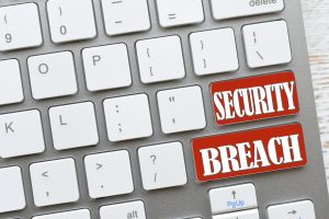 White computer keyboard with red keys that say Security Breach, online dangers Concept hacked